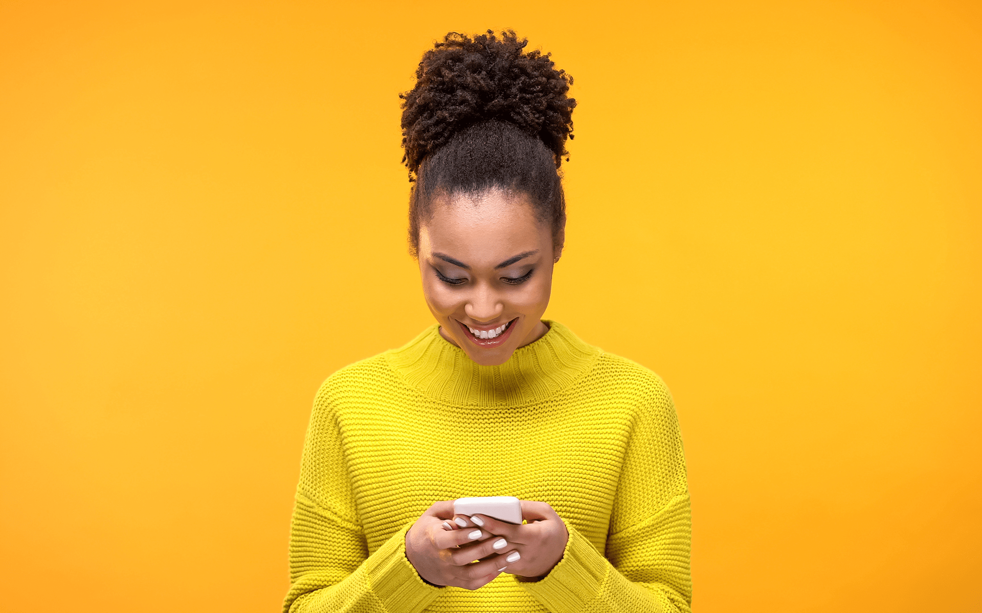 穿着黄色T恤的黑人女性微笑着低头看她的正念订阅，背景为黄色工作室背景。
