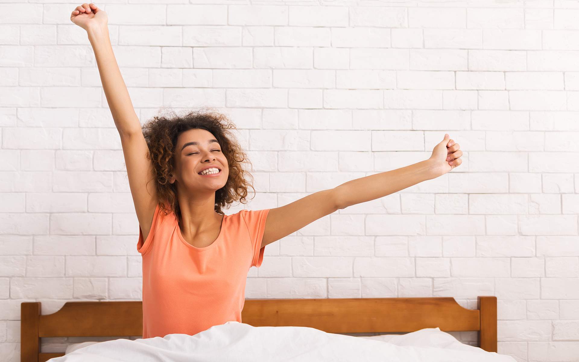 8 科学支持的更好睡眠小贴士 - 非洲裔美国女性在床边伸展，懒洋洋的早晨