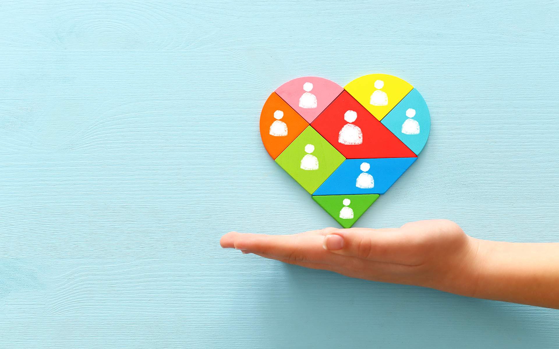 与协作领导导师Miki Kashtan的问答 - 心形拼图块图标覆盖在木桌上，代表人力资源和管理概念