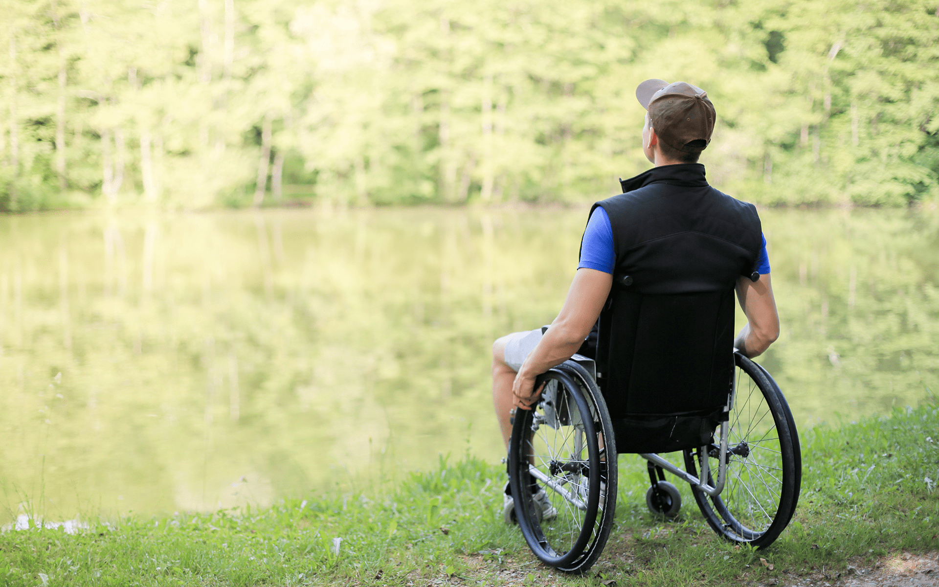 快速提示将正念练习带到户外—一名年轻白人男性坐在轮椅上面对湖泊，周围是绿色的树木