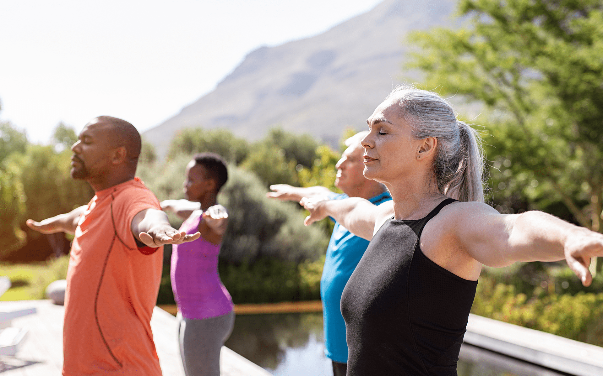 心理健康是你锻炼常规的一部分吗？—一群四名成年人在户外一起做瑜伽。