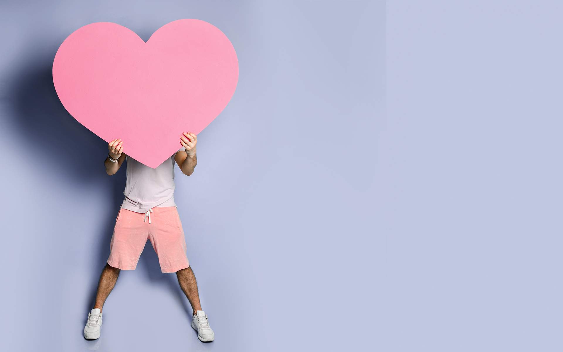 慈心引导冥想 - 年轻男子用粉色心形玩具遮住脸