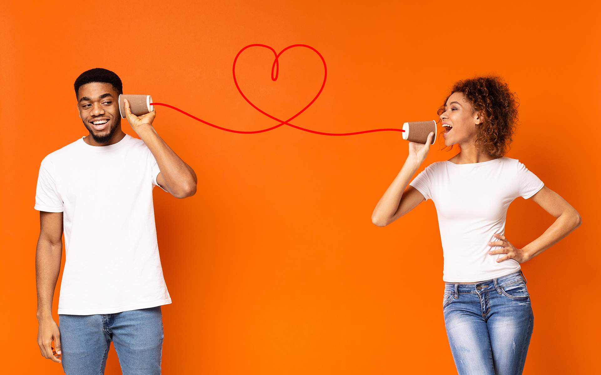 连接对你意味着什么？ - 微笑的男人通过手机听女朋友说话，橙色工作室背景