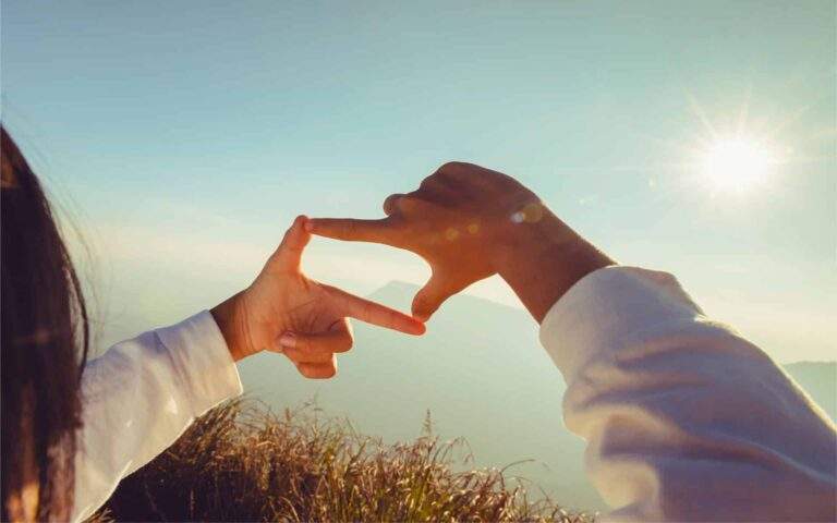 一个12分钟的冥想,扩展你的视角——女人用手框住日出。