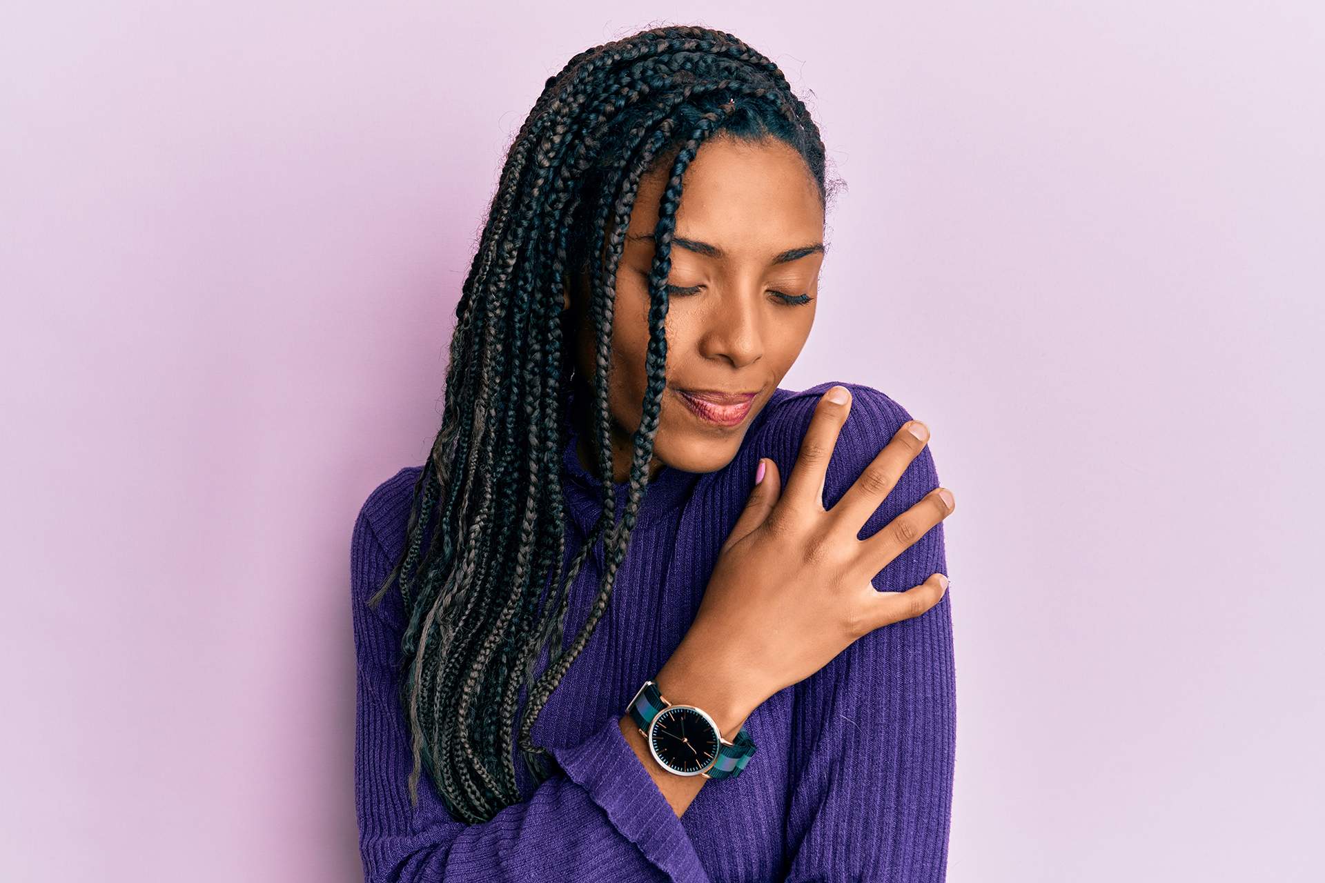 穿着休闲冬衣自信微笑的非裔美国女性，拥抱自己，表现自信和积极的自我关爱